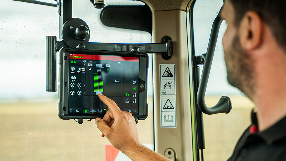 Close-up of a man in the cab of a tractor, using the Väderstad E-Control on an iPad.
