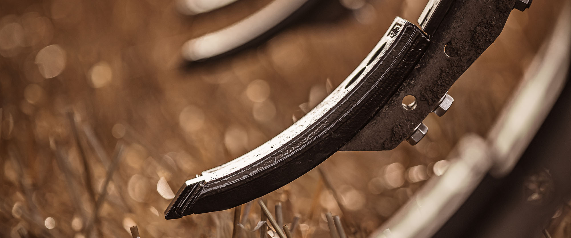 Close-up of Väderstad cultivator points with a field in the background.